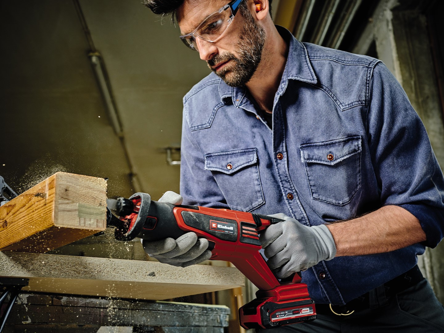 A man cuts a pole with a cordless saw